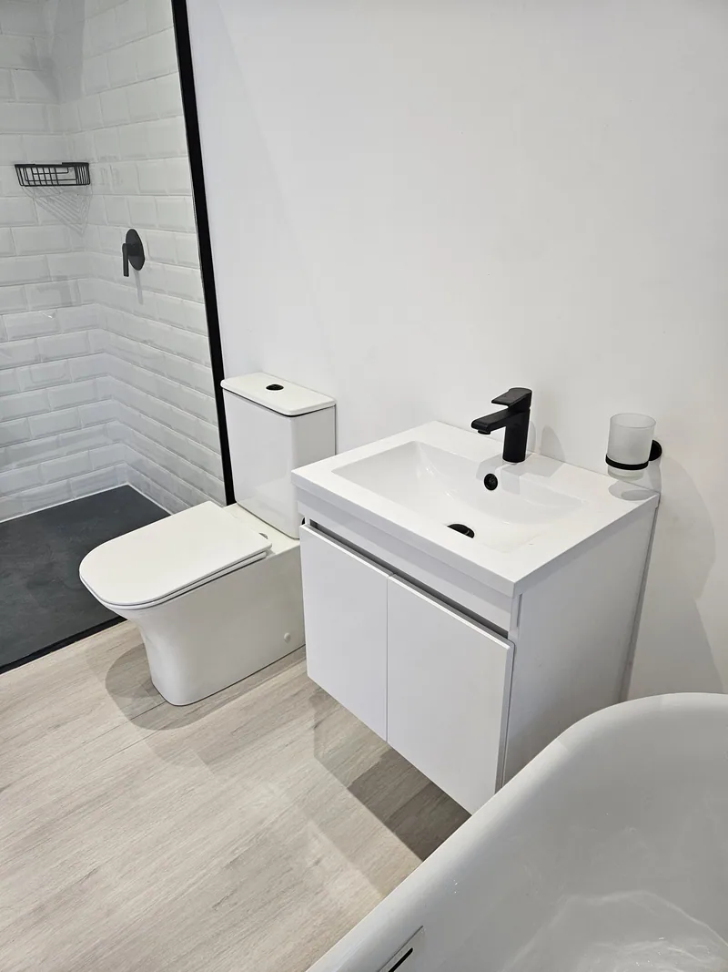 One Bedroom Pod bathroom detail showing the white vanity, toilet and bath beside the tiled wall