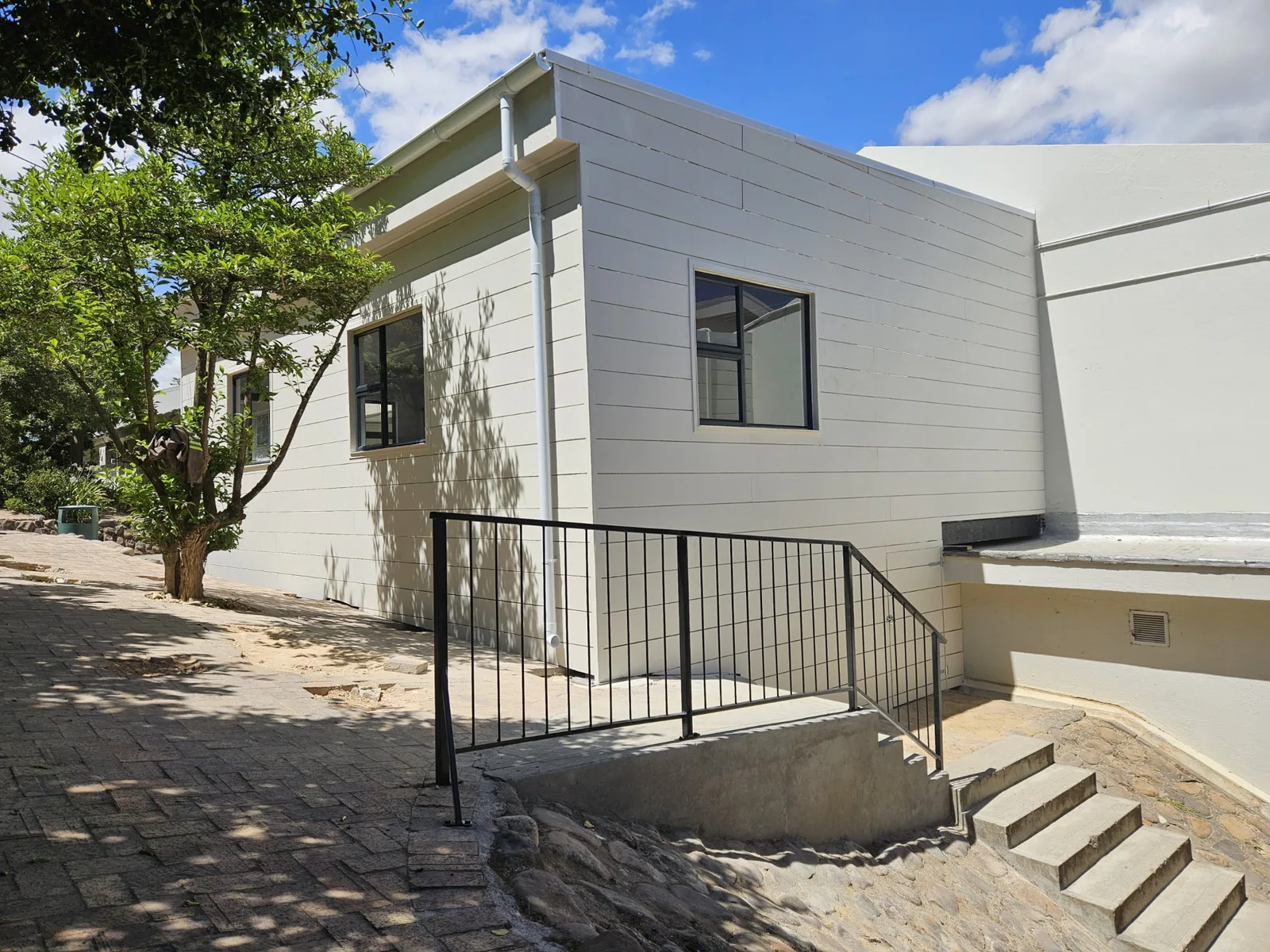 Side elevation of the completed timber frame art classroom with gutter, downpipe and steel handrail to the entrance ramp