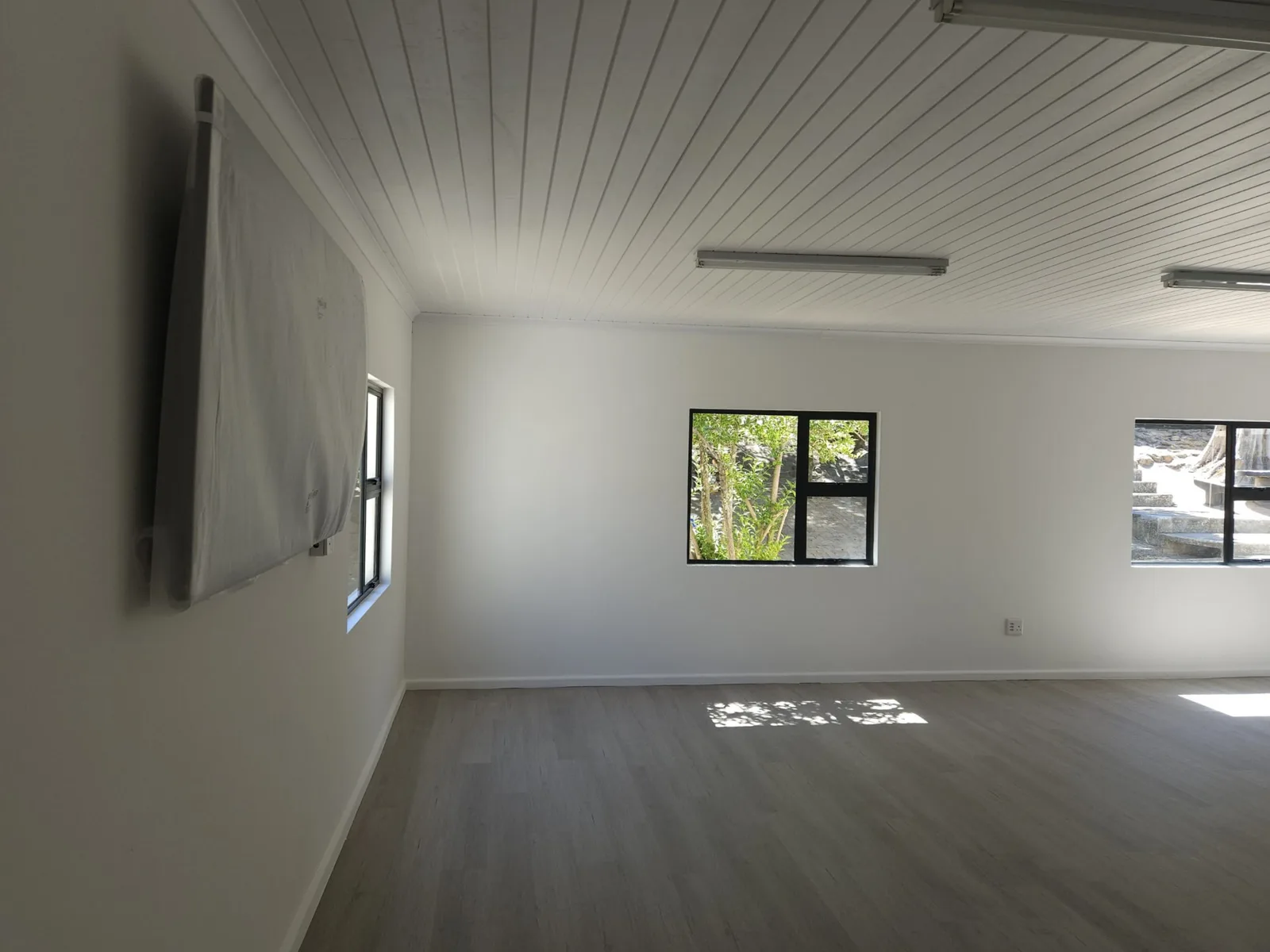 Art classroom interior corner showing the tongue-and-groove ceiling, black-framed windows and wall-mounted board