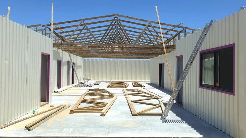 Interior of the shell during construction with timber roof trusses over the finished floor slab