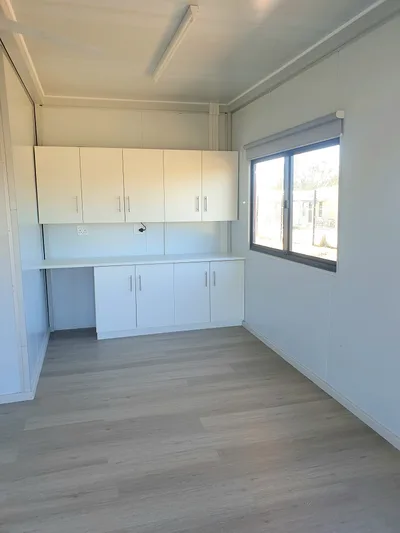 Office with fitted overhead cupboards, desk counter and window blind