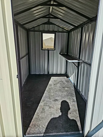 Interior of the garden shed showing the ribbed steel walls, apex roof, window and side shelf