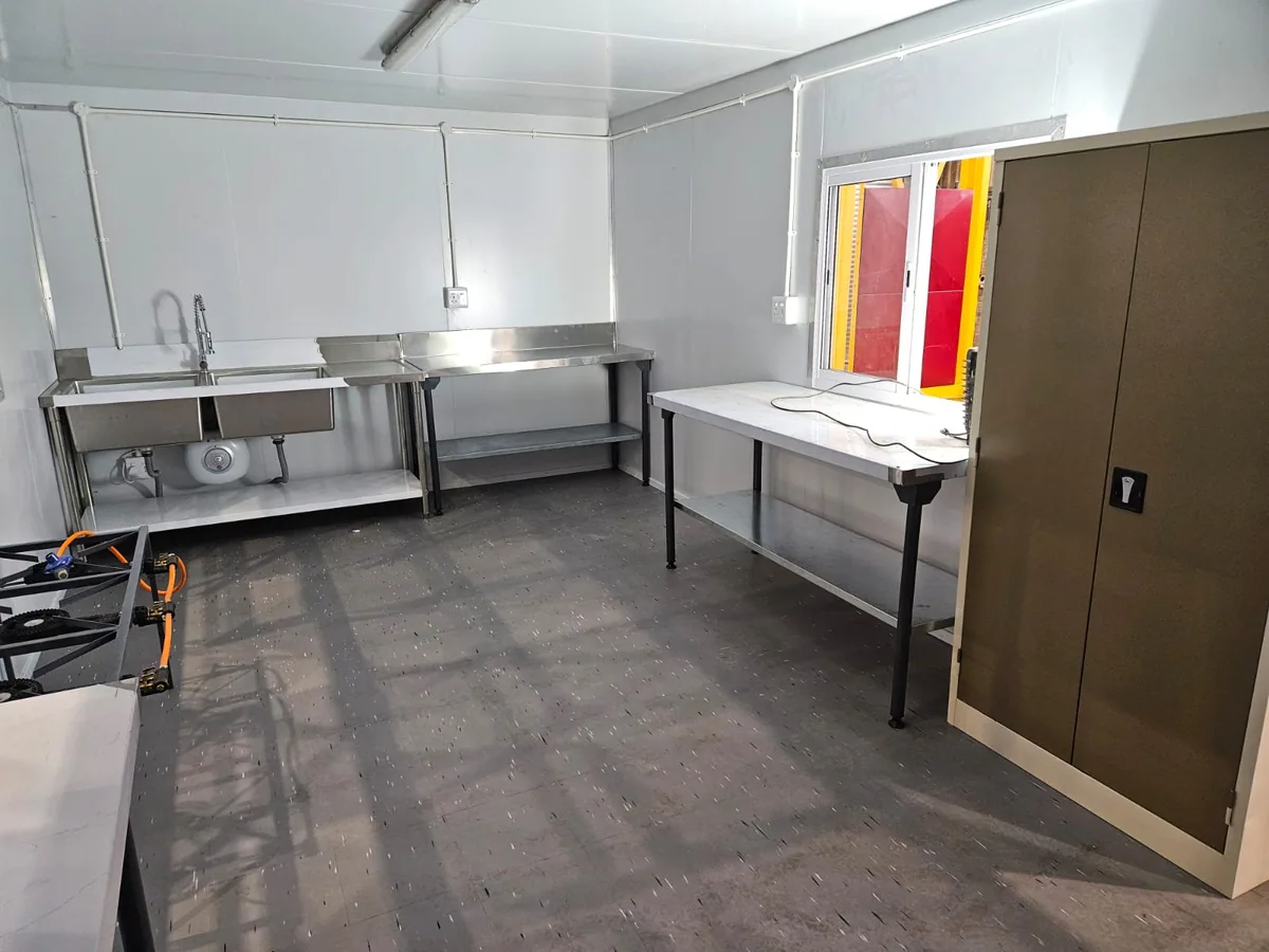 Fitted kitchen interior with stainless steel prep tables, a double sink and a brown storage cupboard