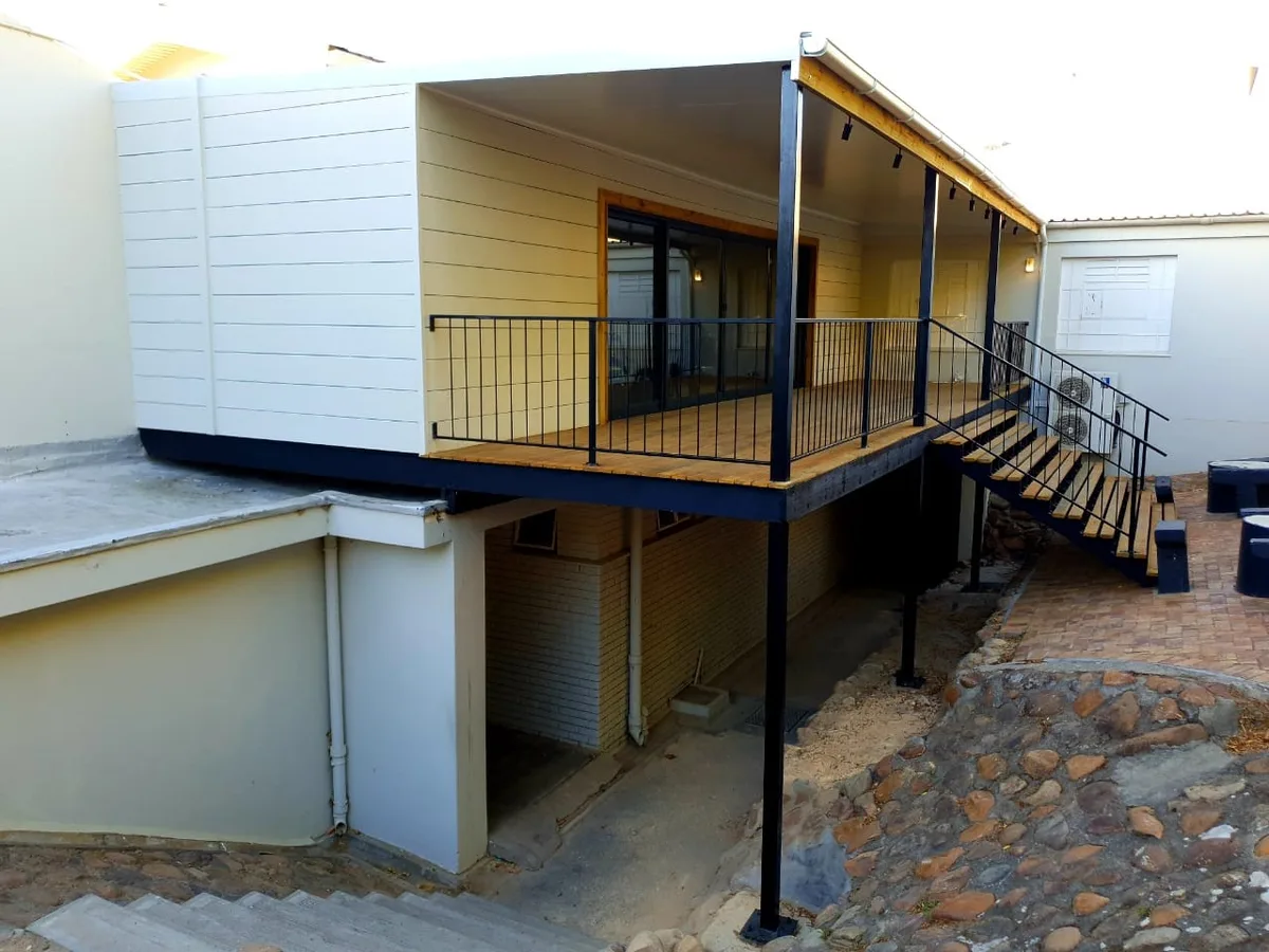 Side view of the elevated music room structure showing the steel deck frame, cladding and access stairs
