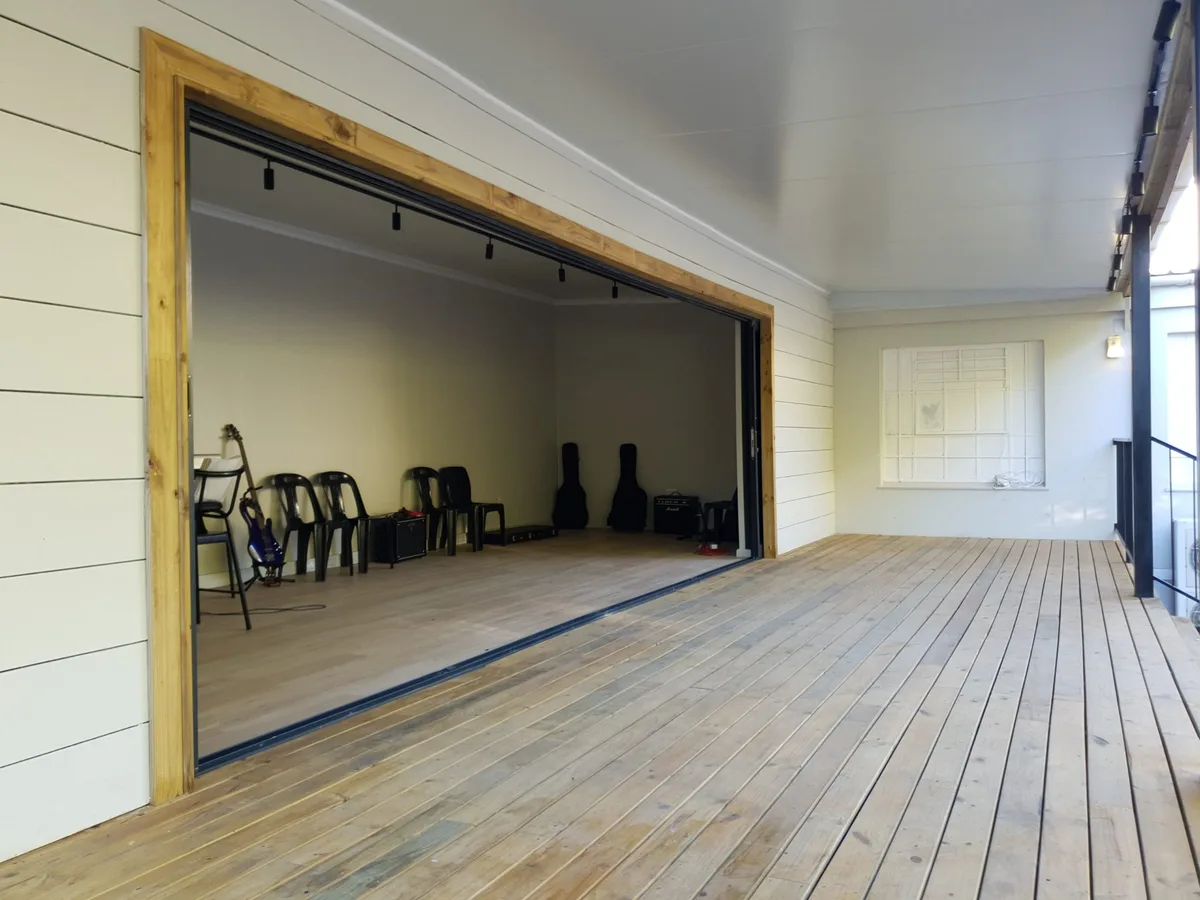Open sliding doors framed in timber, looking into the music room from the deck