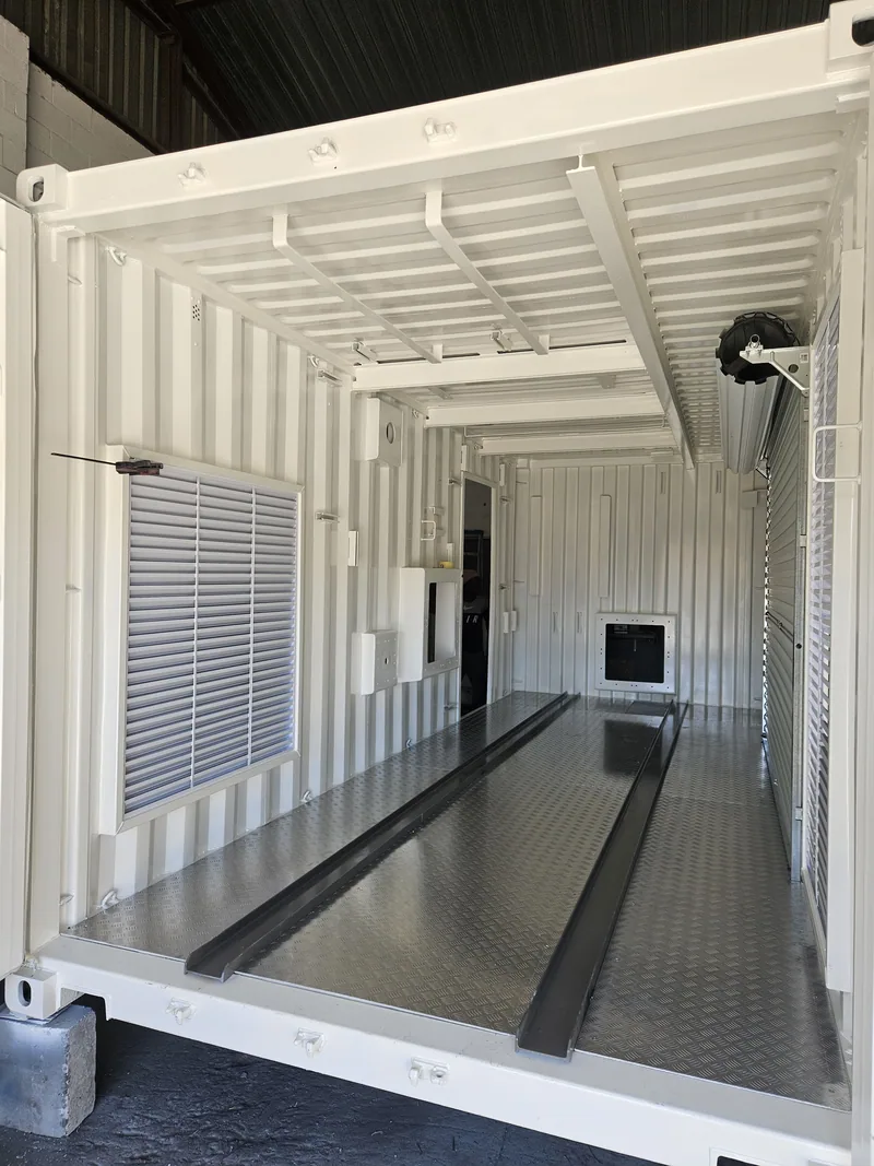 Container interior with a roller shutter door, wall vent and a steel channel set into the floor